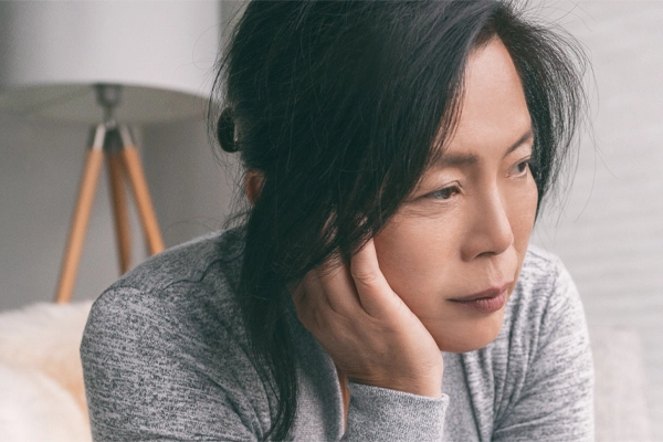 Adrenal-Fatigue-Doctor A middle-aged asian woman sitting on her couch, resting her head on her hand, suffering from adrenal fatigue. Get treatment for adrenal fatigue syndrome from Markham Natural Health Centre in Greater Toronto.