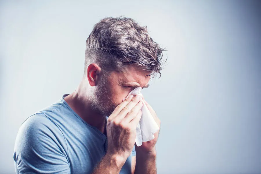 Allergies-Doctor A man in a gray shirt blows his nose. Get help for allergies from Markham Natural Health Centre in Greater Toronto.