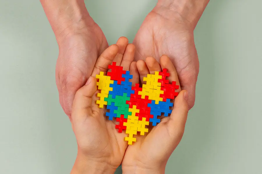 Autism-Clinic A pair of adult hands and a pair of children's hands hold a heart-shaped puzzle. Schedule treatment for autism from Markham Natural Health Centre in Greater Toronto.