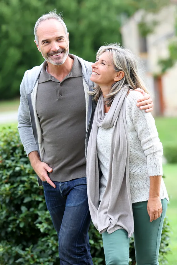 Bioidentical-Hormone-Therapy-Treatment A mature couple in gray toned clothes and jeans walk happily outside, happy with their successful bioidentical hormone treatments from Markham Natural Health Centre in Greater Toronto.