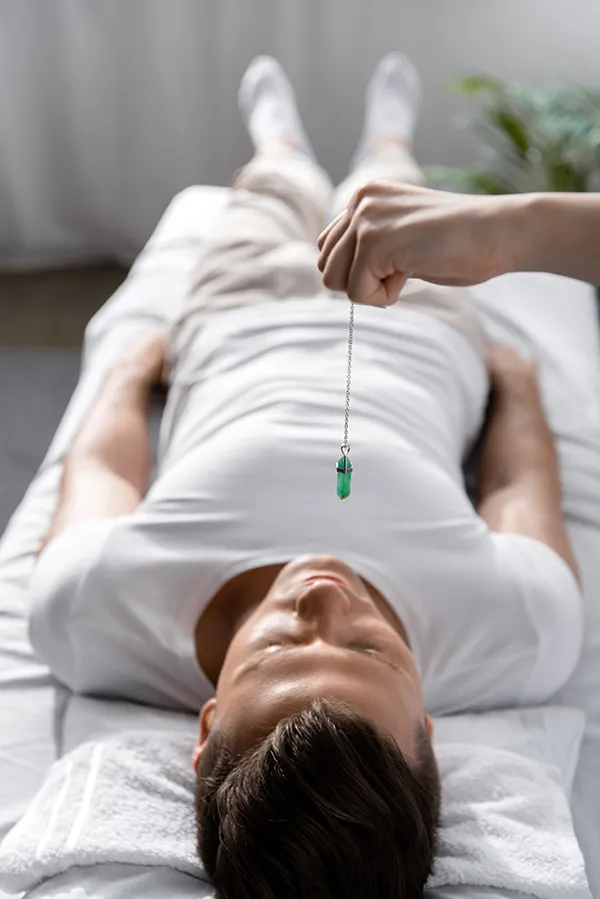 Hypnotherapy-Treatment A man lays on a couch while a hypnotherapist holds a crystal over him. Get hypnotherapy from Markham Natural Health Centre in Greater Toronto.