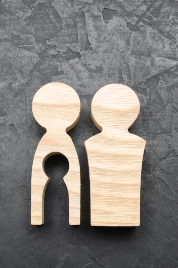 Infertility-Treatment Woodcut figures of a man and woman with a child-shaped area cut out from the woman figure. Get treatment for infertility from Markham Natural Health Centre in Greater Toronto.