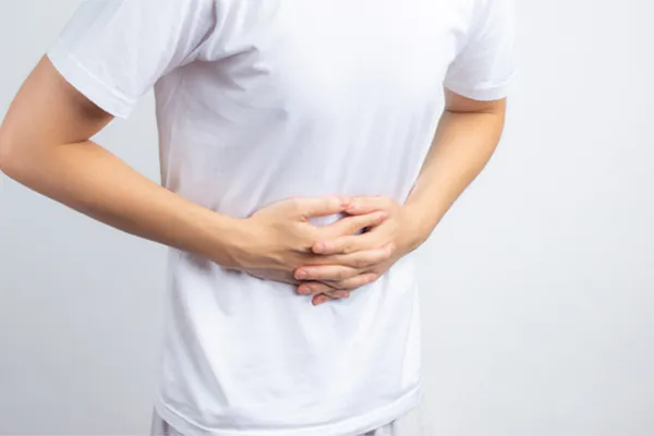 Irritable-Bowel-Syndrome-Clinic A person holding their stomach in visible discomfort against a plain background. Markham Natural Health Centre treats irritable bowel syndrome with functional medicine in Greater Toronto.