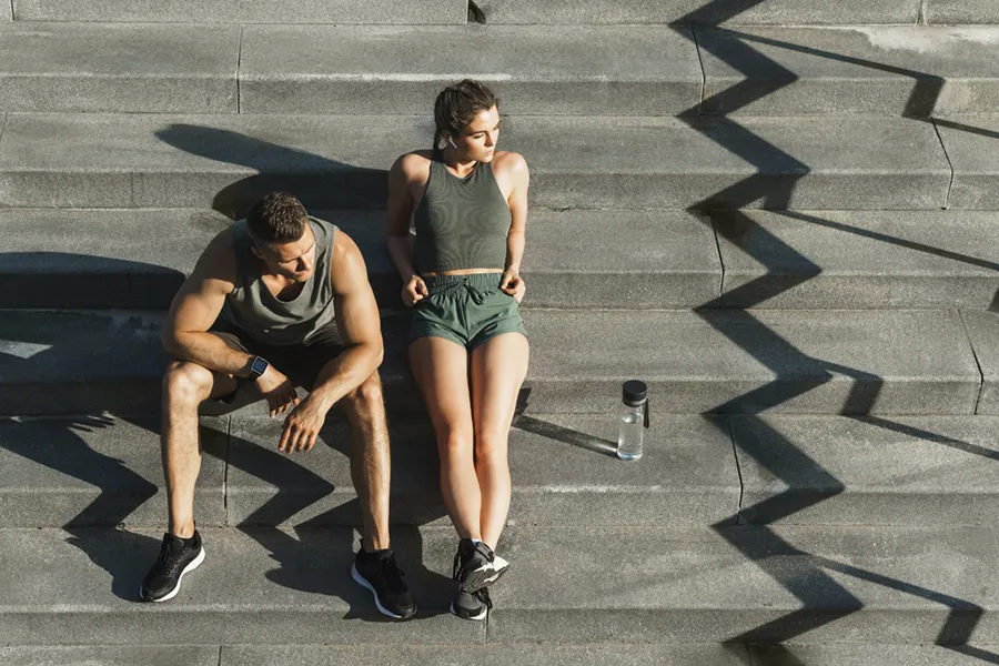 Medical-Weight-Loss-Doctor A couple in gray and green track clothes resting after a workout on stone steps, happy with their weight loss plans from Markham Natural Health Centre in Greater Toronto.
