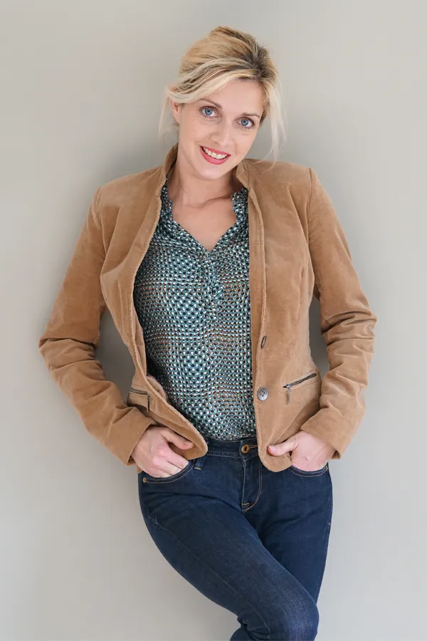 Metabolic-Syndrome-Treatment A smiling blonde woman in a tan leather jacket leans against a gray wall. Schedule metabolic syndrome from Markham Natural Health Centre in Greater Toronto.