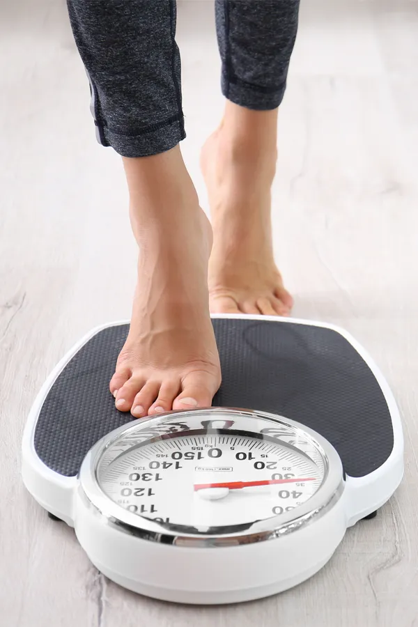 Obesity-Treatment Close up of feet stepping onto a scale. Receive expert functional medicine for obesity treatment by Markham Natural Health Centre in Greater Toronto.
