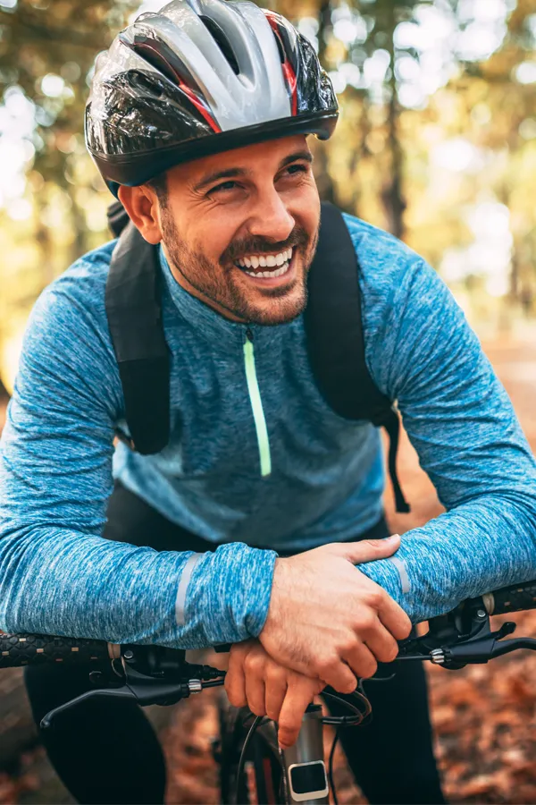 Testosterone-Low-T-Solutions-Treatment A middle-aged man on a trail in cycling clothes is smiling and leaning on his bike's handlebars. Get testosterone for Low T from Markham Natural Health Centre in Greater Toronto.