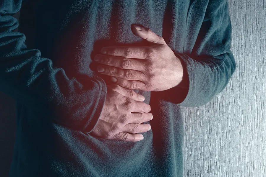 Ulcerative-Colitis-Clinic Close-up of the midsection of a man in a green sweater clutching his gut in pain. Get treatment for Ulcerative Colitis from Markham Natural Health Centre in Greater Toronto.